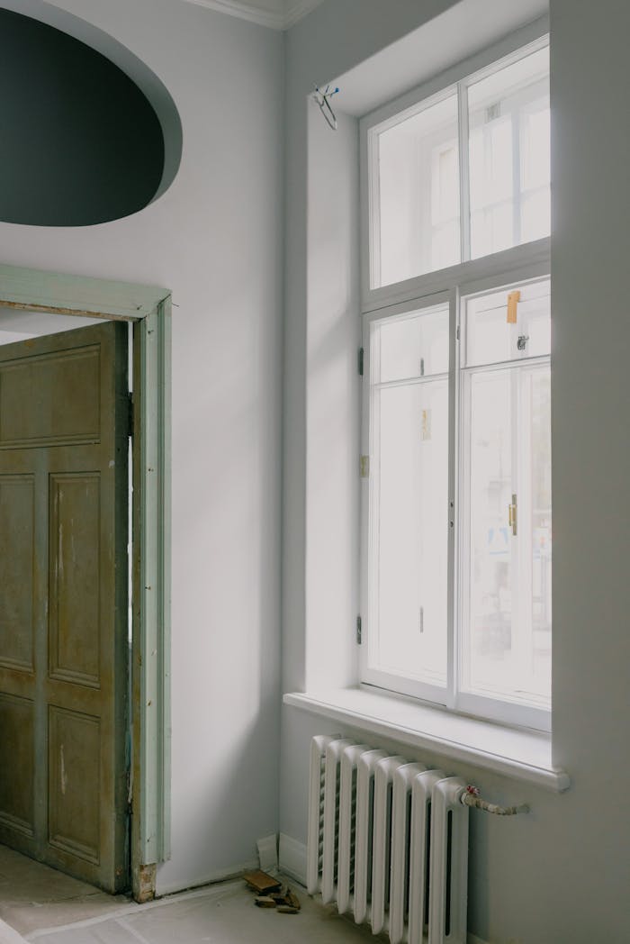 A serene and stylish interior featuring a large window and radiator under soft daylight.